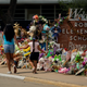 Visitors walk past a makeshift memorial honoring those recently killed at Robb Elementary School, Tuesday, July 12, 2022, in Uvalde, Texas. A Texas lawmaker says surveillance video from the school hallway where police waited as a gunman opened fire in a fourth-grade classroom will be shown this weekend to residents of Uvalde.